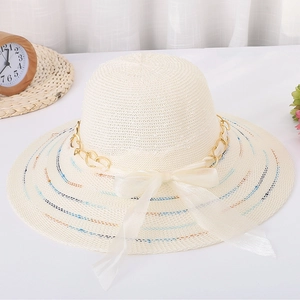 Détail du chapeau de soleil crème avec chaîne dorée, nœud en ruban et paille tressée