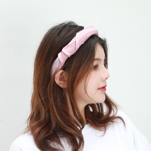 Detailed view of a pink fabric headband with silver jacquard pattern on a female model