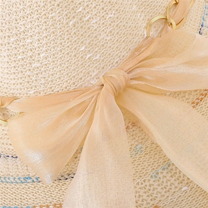 Détail de chapeau de soleil d'été avec texture tissée, chaîne dorée et nœud en tulle