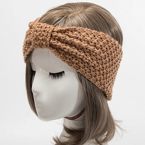 Detail eines handgestrickten breiten Stirnbands in Karamelbraun mit Kreuzknoten