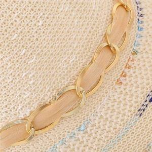 Détail de la chaîne dorée et du ruban en soie rose sur un chapeau de paille d'été