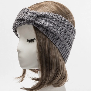 Detailed close-up of dark grey knitted headband with twist design on a model