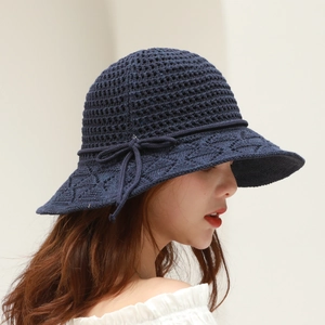Detail of navy blue crochet bucket hat featuring delicate knit bow and wavy brim pattern