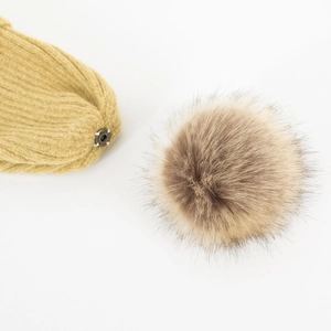 Gele gebreide muts met afneembare bruine bontpompom en metalen drukknop detail