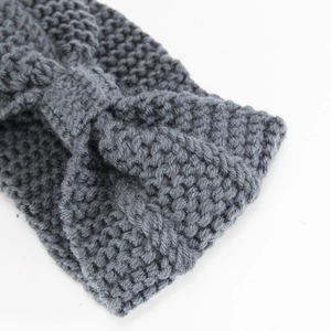Close-up of grey knitted headband with thick texture and stylish knot design detail