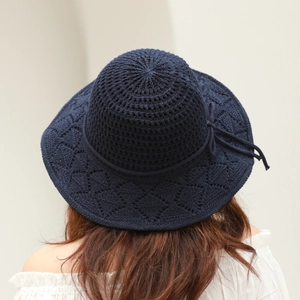 Detail of navy knit sun hat featuring elegant bow and intricate hollow-out weave pattern