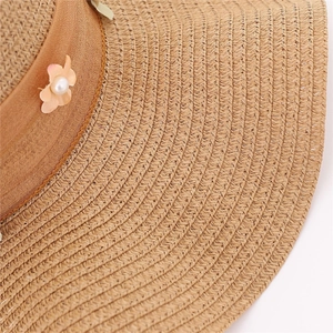 Dettaglio della trama in paglia con fiore rosa e perla bianca sul cappello da sole