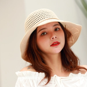 Detail of beige straw sun hat with hollow knit pattern and wide brim on a model