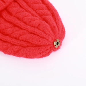 Macro shot of red cable-knit texture showing thick stitching and vintage metal snap button