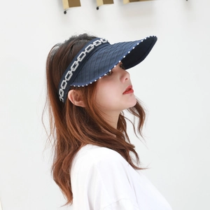 Detail of dark blue sun visor hat with white polka dots and silver chain pattern