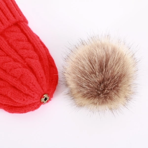 Detail of red cable knit beanie featuring a detachable faux fur pom-pom with snap button
