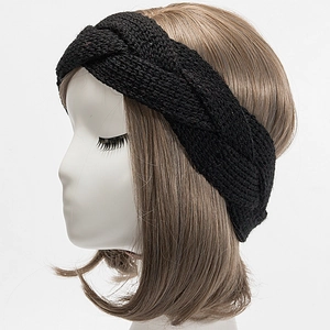 Detail of a thick black cable-knit headband worn by a model for winter warmth