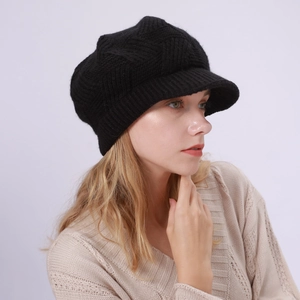 Close-up of black knitted newsboy cap featuring diagonal textures and soft brim detail