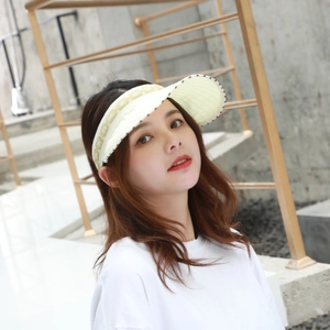 Close-up of beige sun visor cap with golden letter embroidery and modern chic details