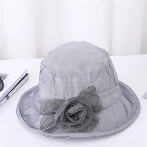 Detail of grey sun hat with large floral fabric ornament and textured surface