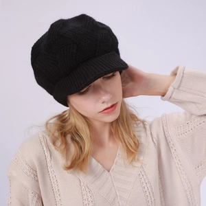 Detailed close-up of a black knit newsboy cap featuring a textured diamond pattern