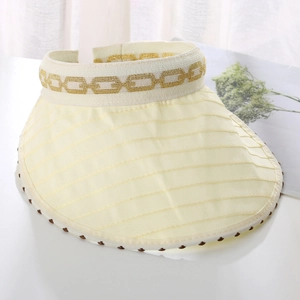 Close-up of beige sun visor with golden chain pattern and decorative beaded edge texture