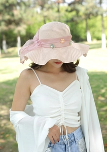 Dettaglio cappello da sole rosa con fiocco in chiffon e fiori di perle fatti a mano