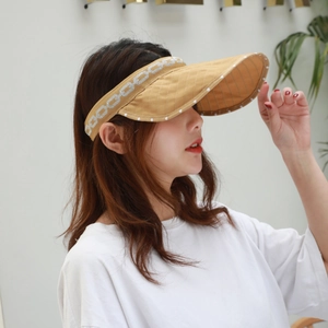 Detail of khaki sun visor with white polka dots and silver chain pattern on headband