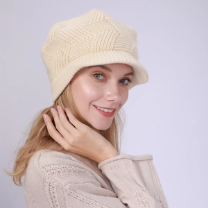 Detail of elegant cream-white knit peaked cap featuring textured diamond patterns and soft brim
