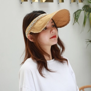 Detail of khaki sun visor with polka dot brim and chain-knit headband on female model