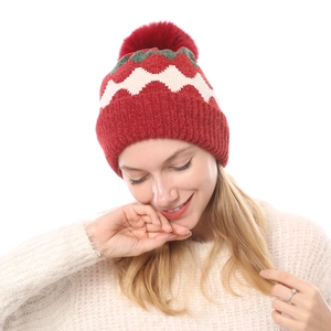 Detail der Strickmütze mit Wellenmuster in Rot und Grün sowie weichem Kunstfell-Bommel