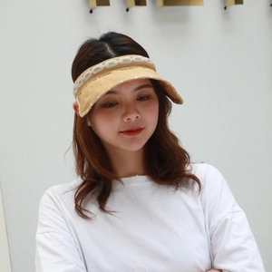 Detail of light khaki sun visor hat with white chain geometric print worn by a model