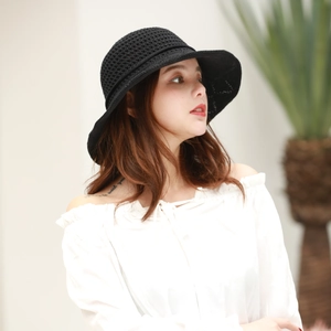 Detail of black woven sun hat featuring a breathable hollow knit design and wide brim
