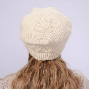 Detailed texture of the cream knit beanie featuring thick ribbing and warm wool finish