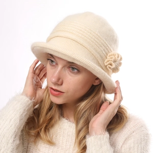 Detail of a cream knit cloche hat featuring thick warm texture and a handmade flower accent