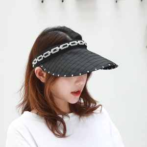 Detail of black foldable sun visor hat showing white polka dots and chain pattern trim