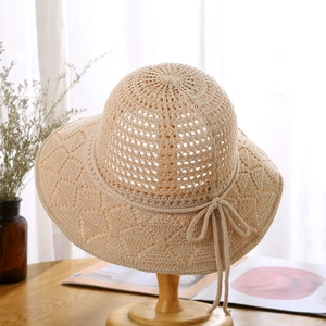 Detail of crochet sun hat featuring diamond hollow pattern and bow tie on a wooden stand