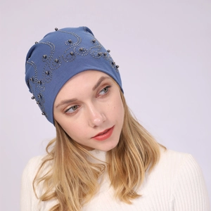 Detailed view of blue cotton slouchy beanie with black pearls and silver stud patterns
