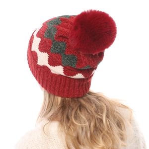Detail einer warmen Strickmütze mit Wellenmuster und großem rotem Bommel für Winter