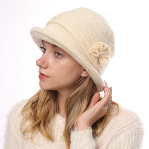 Detail of cream knit bucket hat with floral accent and ribbed wool texture for winter
