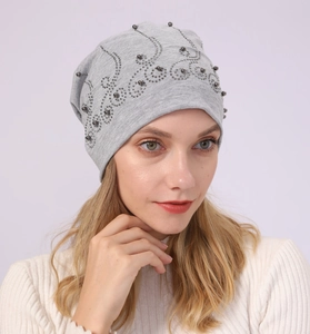 Detail of grey cotton beanie featuring decorative dark beads and sparkling rhinestones