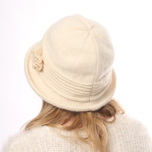 Detail of a beige thick knit bucket hat with a decorative crochet flower on the side