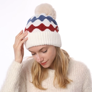 Detail der warmen Winterstrickmütze mit weichem Bommel und farbigem Wellenmuster