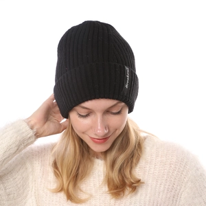 Detail showing Breakout label on black ribbed knit beanie worn by a model in soft light
