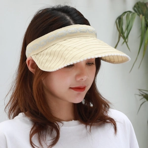 Detail of light beige sun visor with striped brim and silver glitter geometric pattern
