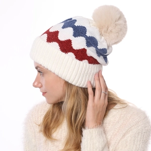 Detail der rot-weiß-blauen Strickmütze mit Wellenmuster und flauschigem Bommel