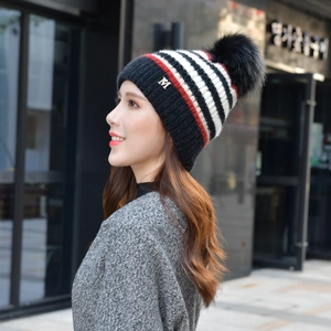 Detail der gestrickten Wintermütze mit bunten Streifen, Kunstfellbommel und M-Logo