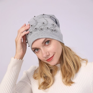 Detail view of light grey cotton beanie with elegant pearl and rhinestone swirl pattern