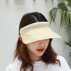 Detail of beige visor hat showing wavy ball trim and elastic chain pattern headband