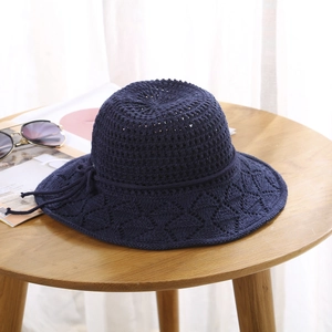 Detail of navy crochet sun hat featuring a hollow-out knit pattern and bow tie accent