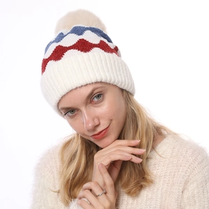 Detail einer Winterstrickmütze mit rot-blauen Wellen und flauschigem Kunstfellbommel