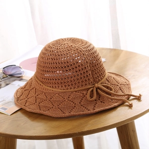 Detailed texture of brown crochet sun hat with hollow knit and bow on wooden table