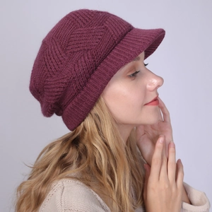 Macro view of burgundy knitted beanie with visor showing detailed herringbone stitch texture