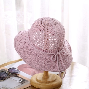 Detail of pink crochet sun hat with hollow knit texture and decorative bow tie