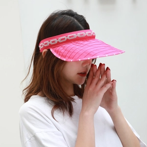 Close-up of bright pink sun visor with silver chain print and white polka dot edge